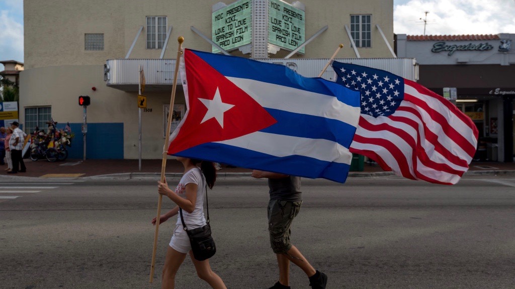 Un hombre y una mujer en Miami, con una bandera cubana y una de EEUU.