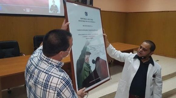 El ministro de Salud Pública, José Ángel Portal Miranda, entrega un reconocimiento al agente Fernando de la Seguridad del Estado.
