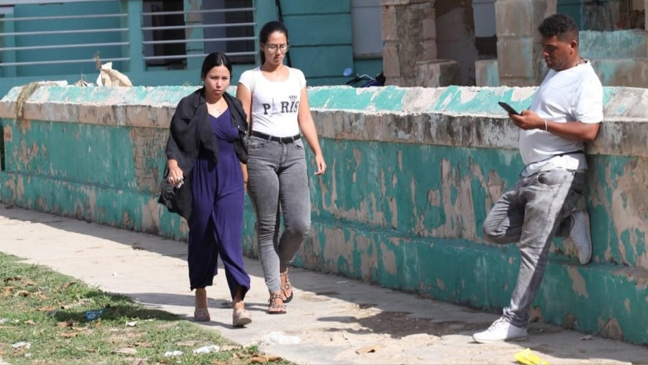 Dos mujeres y un hombre en una calle en Cuba.