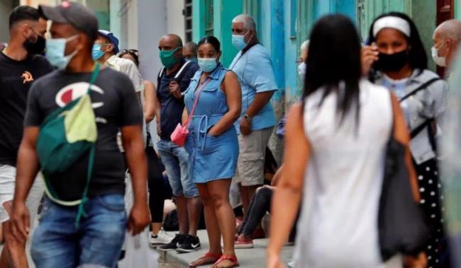 Un grupo de cubanos se concentran en una calle.