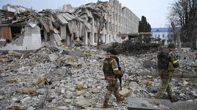 Miembros del ejército ucraniano caminan cerca de un edificio escolar destruido por los bombardeos.