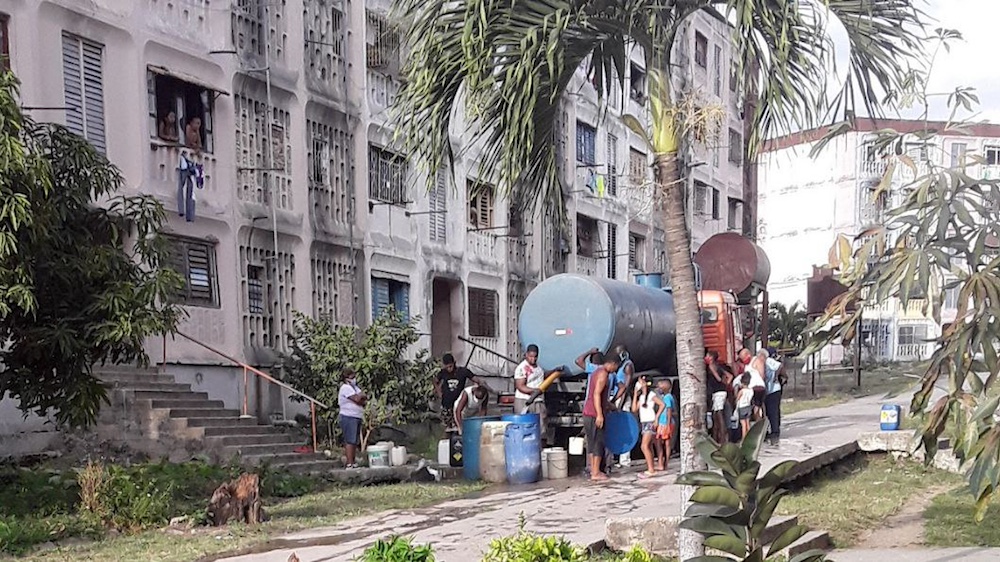 Residentes en Santiago de Cuba recogen agua de una camión cisterna.