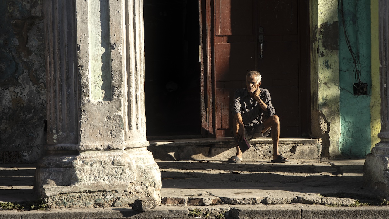 Un cubano sentado a la entrada de un edificio de La Habana.